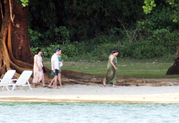 Dilma caminhando na praia ao lado da fam&iacute;lia.